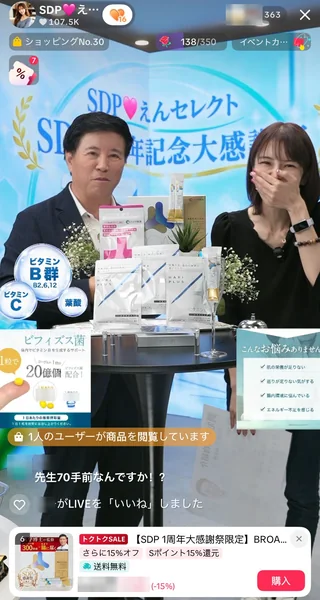 SDP♡えんセレクトの 1周年記念大感謝祭の TikTok LIVE 画面。クリエイターと男性ゲストが、テーブルに並べたビタミンのサプリメントを紹介している